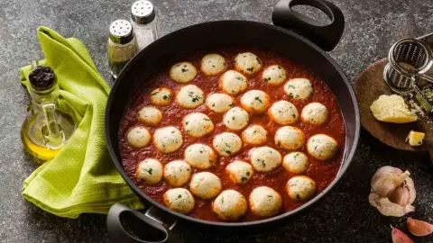 Ricotta guľky podávané v hustej paradajkovej omáčke s bylinkami.