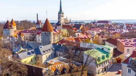 Historické centrum Tallinnu s vežami, hradbami a stredovekou architektúrou pri východe slnka.