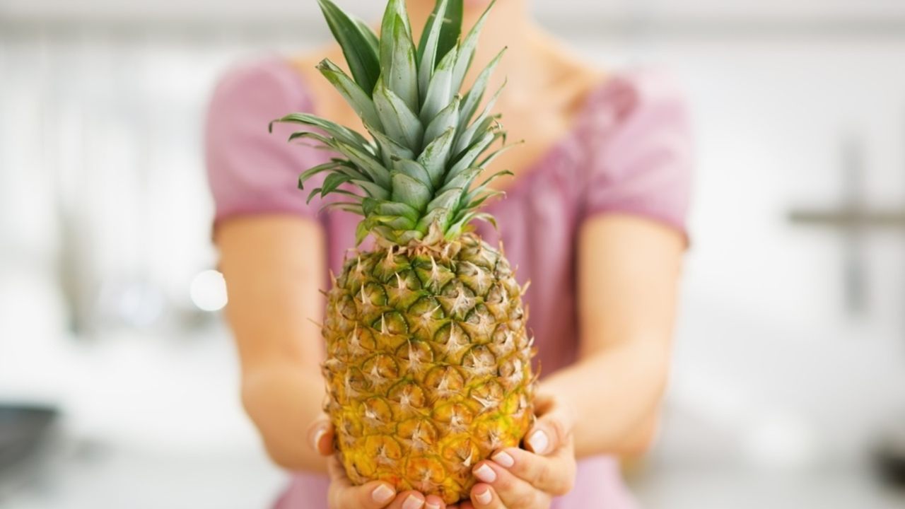 Žena držiaca v rukách čerstvý ananás, ktorý patrí medzi ovocie s najnižším obsahom pesticídov.