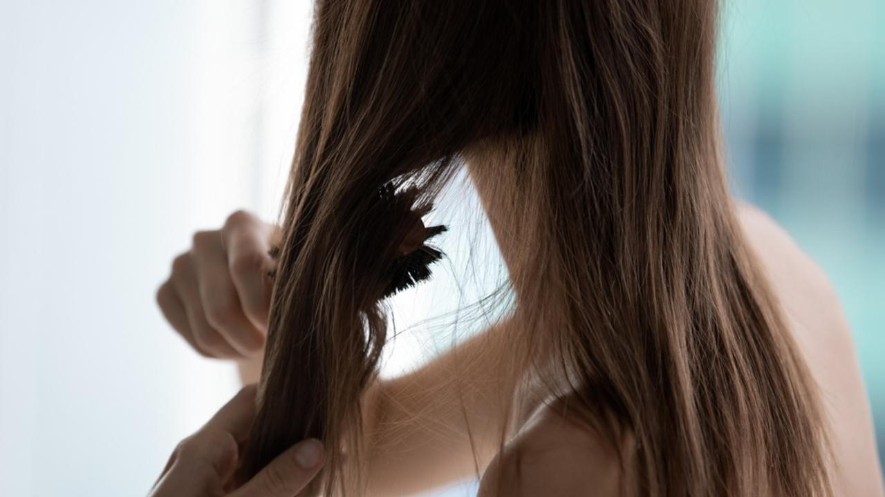 Žena si rozčesáva suché, oslabené vlasy, ktoré stratili lesk počas zimného obdobia.