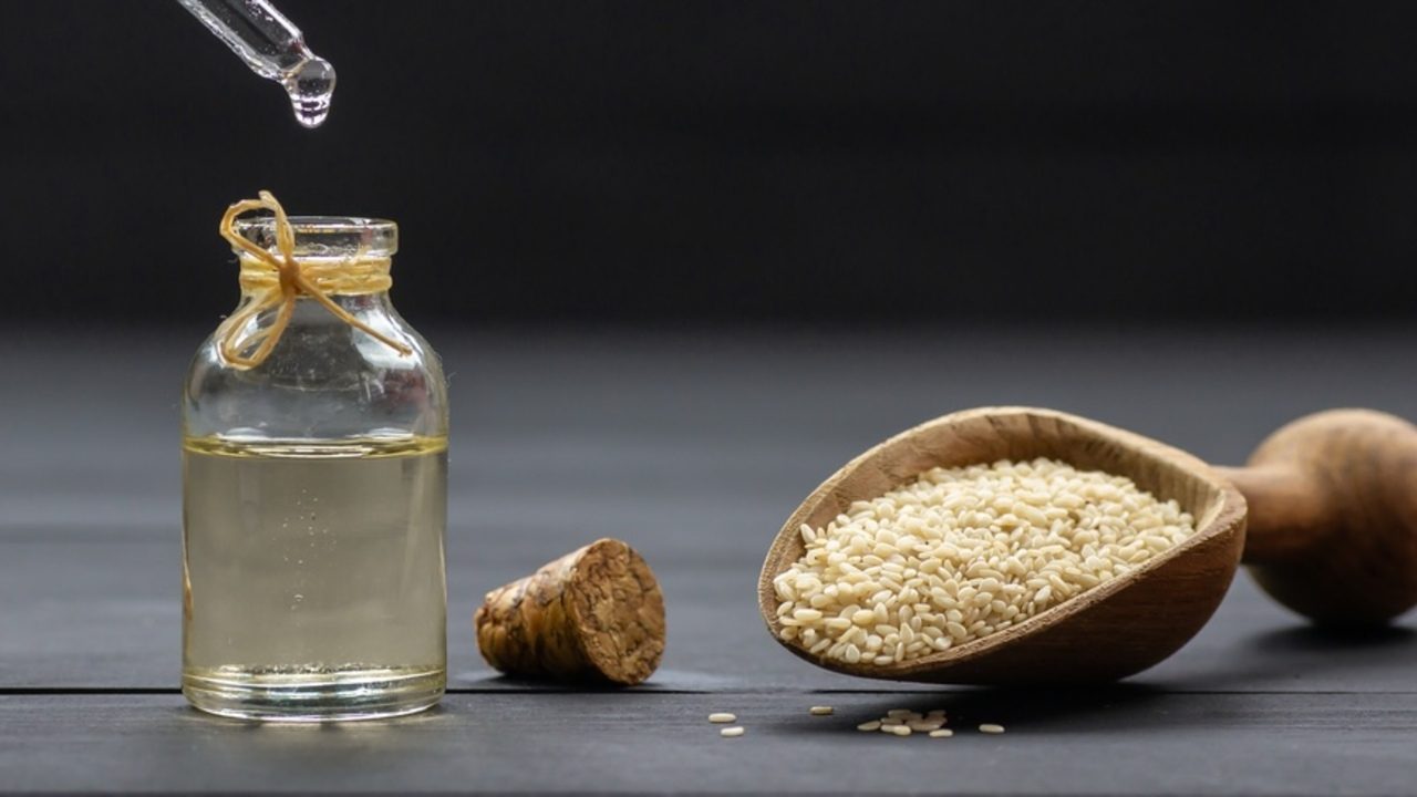 Sezamový olej v sklenenej fľaštičke so sezamovými semienkami ako prírodný elixír pre pokožku