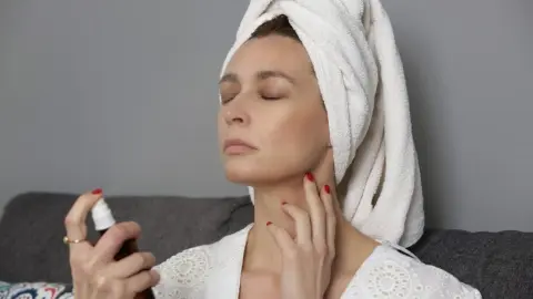Žena si v zime aplikuje pleťové tonikum v spreji pre okamžitú hydratáciu a úľavu