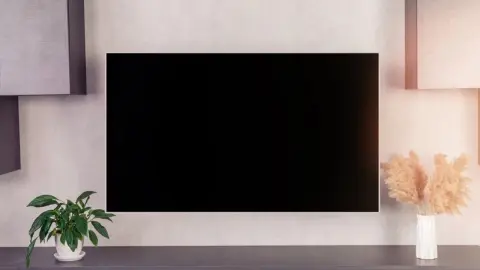 Veľký moderný televízor s prázdnou čiernou LCD obrazovkou zavesený na stene v interiéri domu