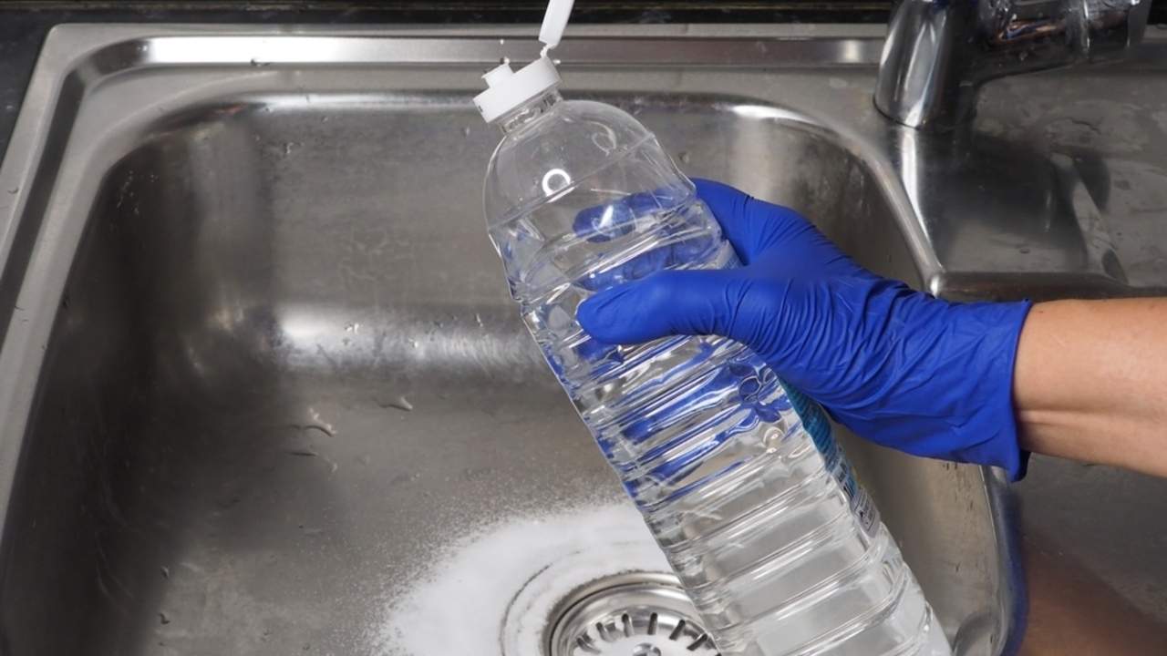 Nalievanie octu do drezu ako domáci spôsob čistenia odpadu.