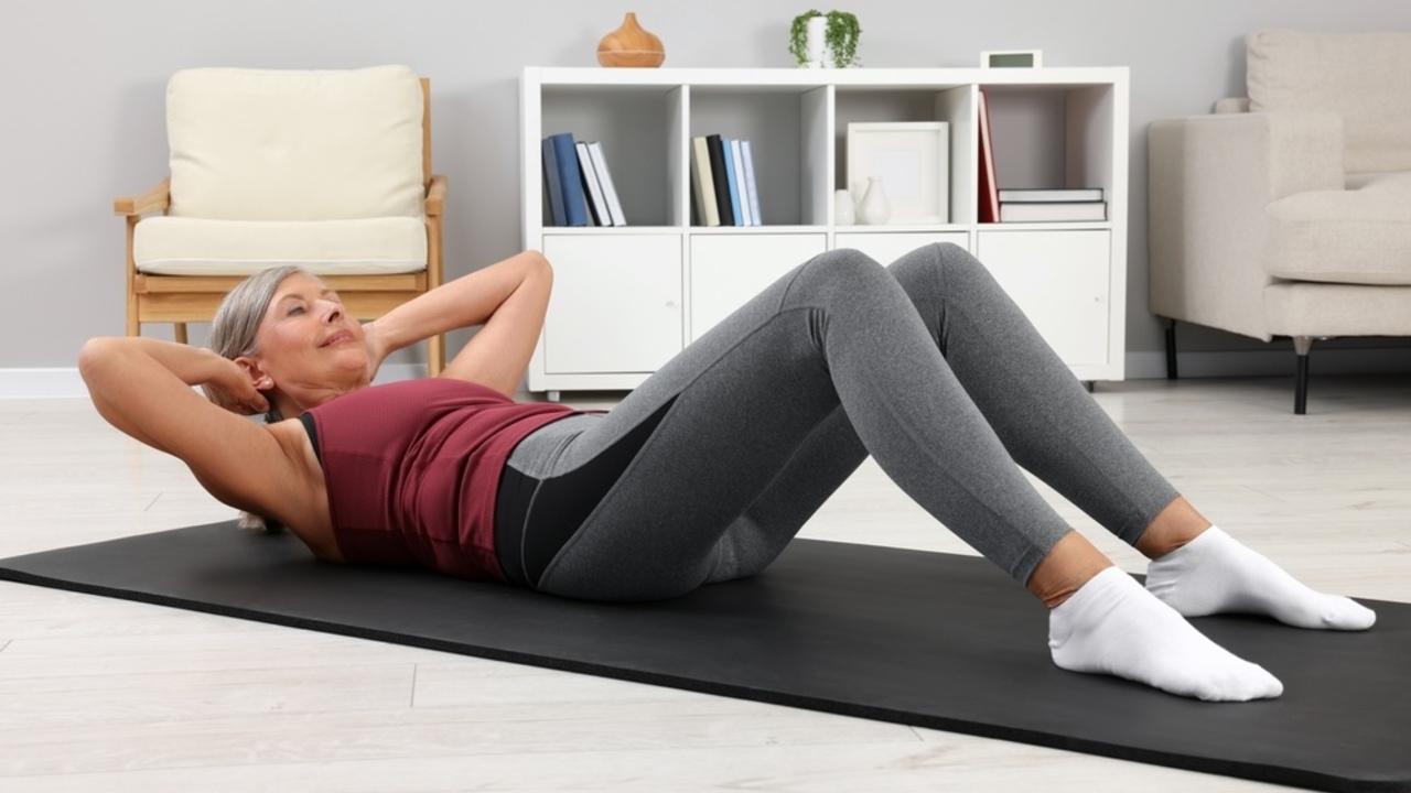 Žena robí brušáky na podložke doma počas tréningu.