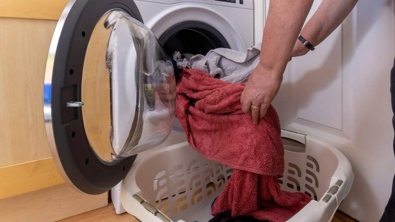 Osoba vyťahuje mokré prádlo z práčky po skončení pracieho cyklu.