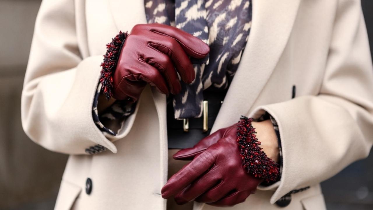 Detail bežového kabáta a vínových kožených rukavíc ako symbol elegantného ženského štýlu.
