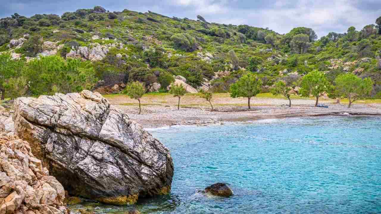 Pláž Iero, ostrov Ikaria, Grécko, zátoka s vlnami Ikarského mora, ktoré v lete omývajú pobrežné skaly pri Dionýzovom jaskynnom chráme.