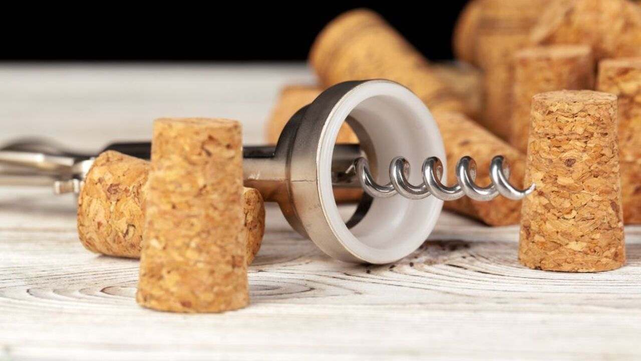 Vývrtka na víno položená medzi viacerými korkovými zátkami na drevenom stole