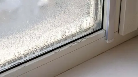 Zahmlené okno s kvapkami vody na vnútornej strane počas zimného obdobia