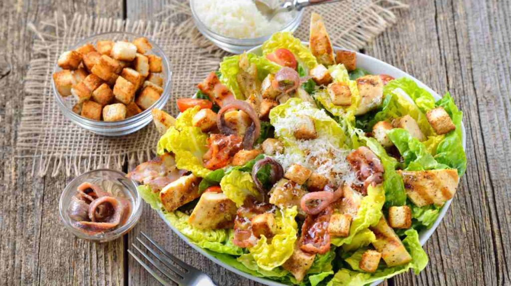 Lahodný caesarový šalát s grilovaným kuracím mäsom, slaninou, krutónmi, filé z ančovičiek a parmezánom