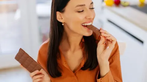 Žena si vychutnáva čokoládu, záber zameraný na konzumáciu sladkostí