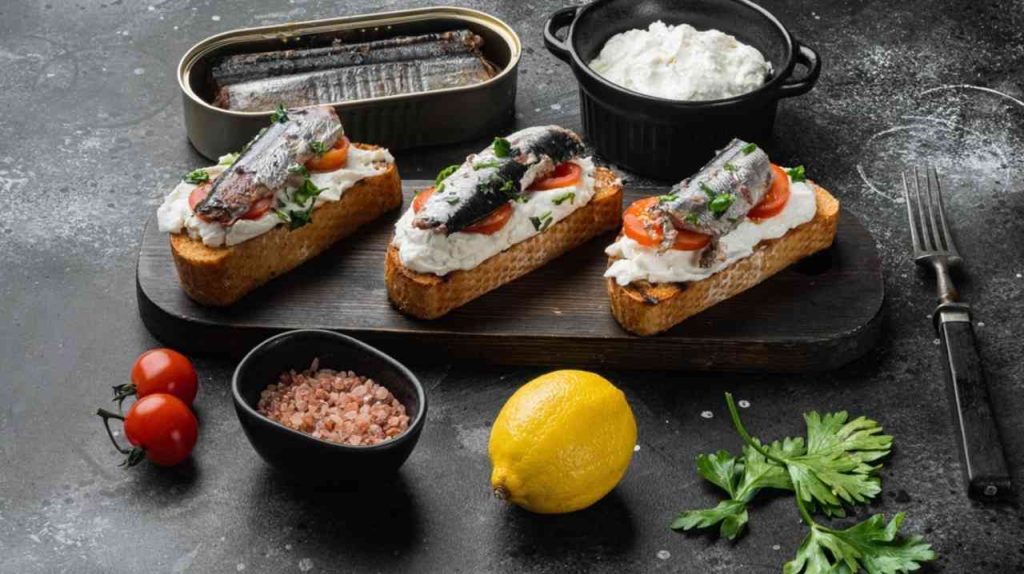 Sendvič so sardinkami a údenou rybou na čiernom kamennom stole