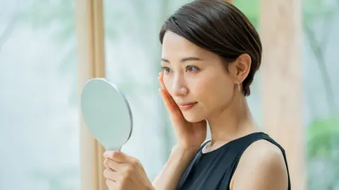 Japonka pri rannej skincare rutine pred zrkadlom