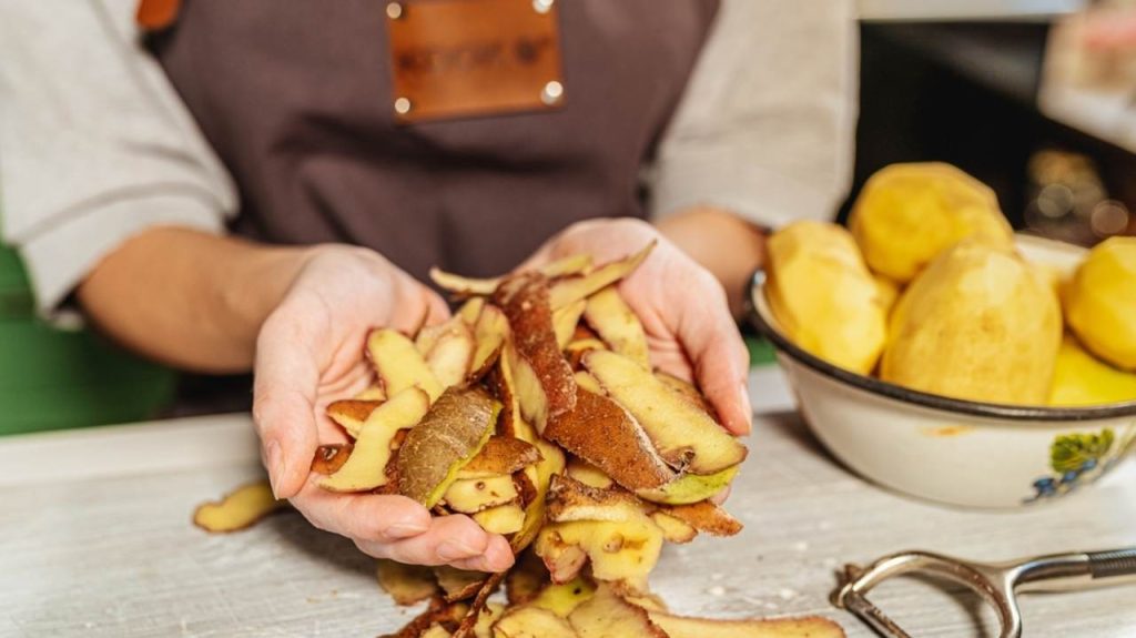 Zemiaková šupka v rukách kuchárky. Využitie a spracovanie potravinového odpadu, kompostovanie, s cieľom zlepšiť úrodnosť pôdy