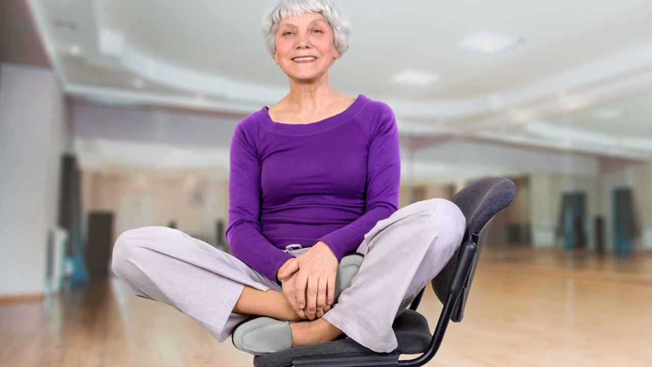 Šťastná, očarujúca a krásna staršia žena cvičí na stoličke. Cvičí gymnastiku pre zdravie vo fitness miestnosti. Športový tréning.