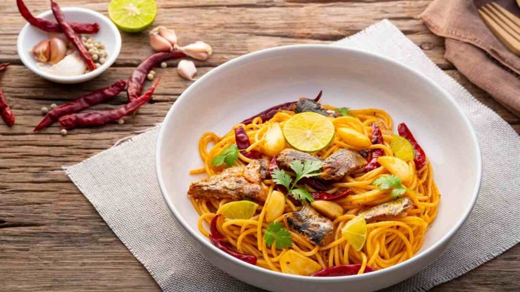 Špagety s makrelou z konzervy a sušenou chilli papričkou s cesnakom na bielom tanieri. Fúzna kuchyňa