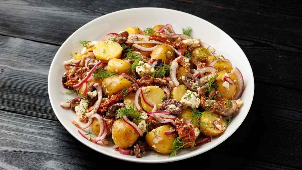 Grécky zemiakový šalát s syrom feta, olivami Kalamata, sušenými paradajkami a červenou cibuľou.