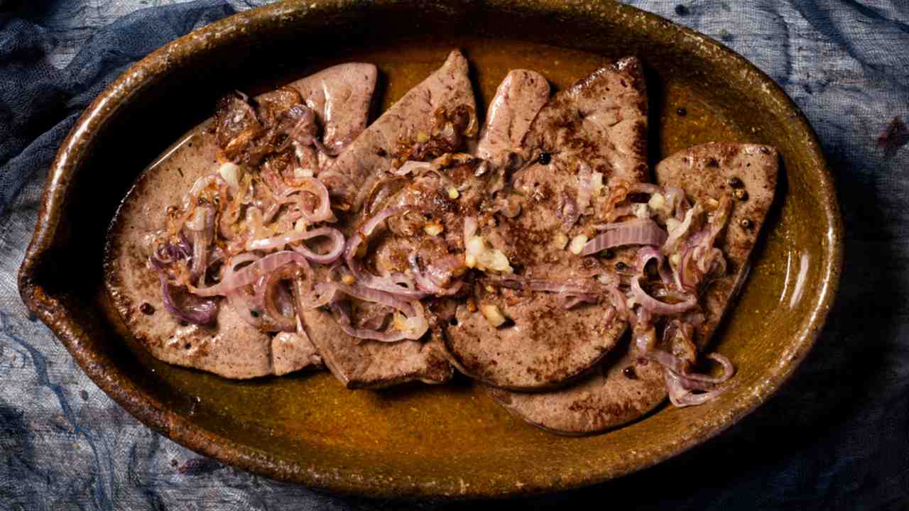 pohľad zhora na „higado encebollado“, španielsky recept na hovädzú pečeň podobný jedlu „pečeň s cibuľou“, podávaný v hnedom hlinenom pekáči