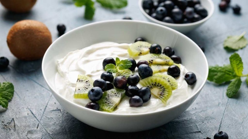 Grécky jogurt s čerstvými čučoriedkami a kiwi. Zdravé raňajky s probiotikami