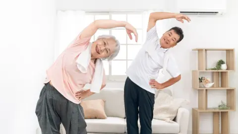 Starší muži a ženy cvičiaci doma (rozhlasová gymnastika)