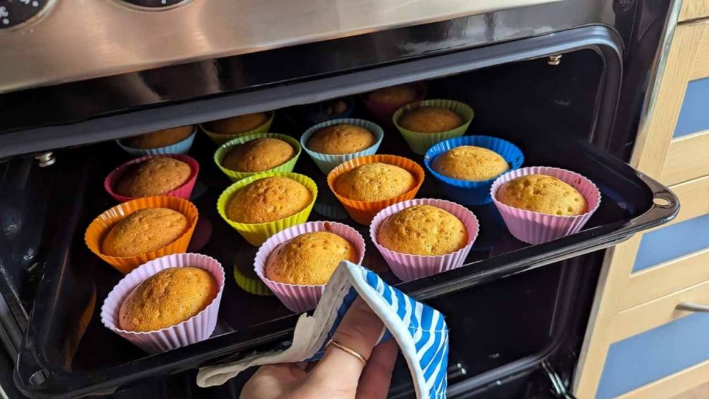 Zlatisté, nadýchané cupcakes, ktoré práve vyšli z rúry, uložené v farebných silikónových formičkách na opakované použitie. Ideálny motív pre jedlo, dezerty, domáce pečenie a sladké kulinárske nápady